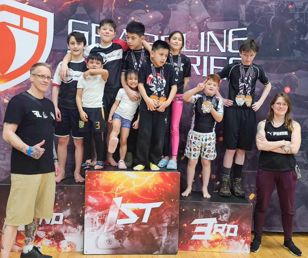 Eight Day Martial Arts owner and coach Bobby Woodman, left, and coach Demie Leduc, right, stand with the club&rsquo;s youth team, which competed at the Grappling Industries tournament in Vancouver on Jan. 31. (Kevin Ceniza/Submitted)